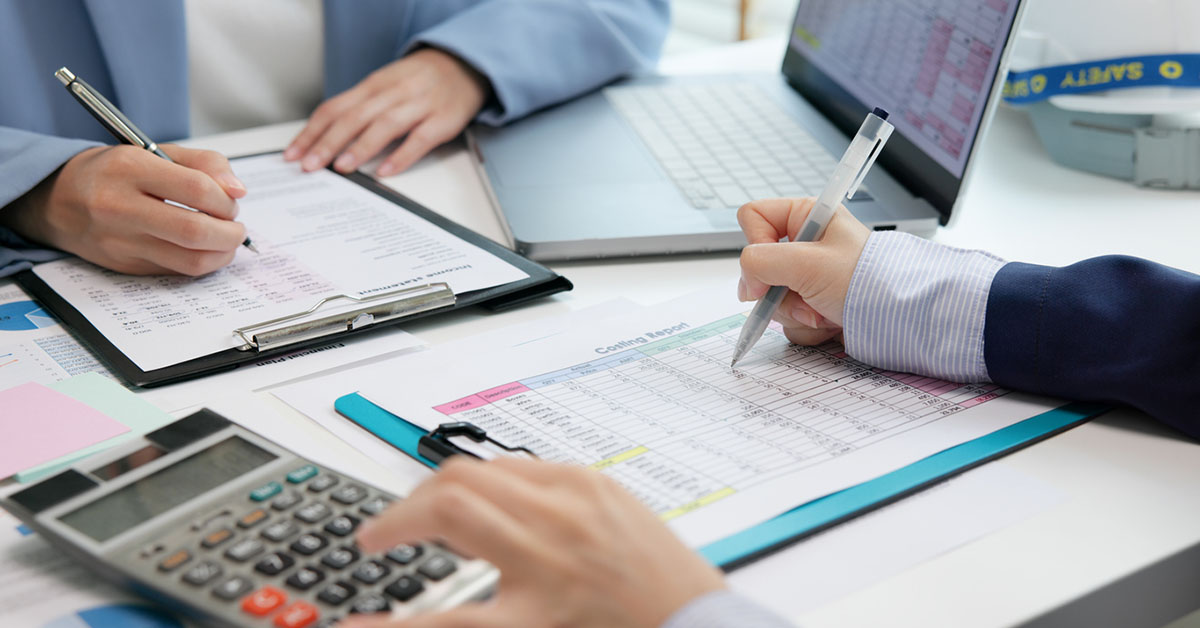 外資系企業の経理担当者が決算資料と財務レポートを確認する業務風