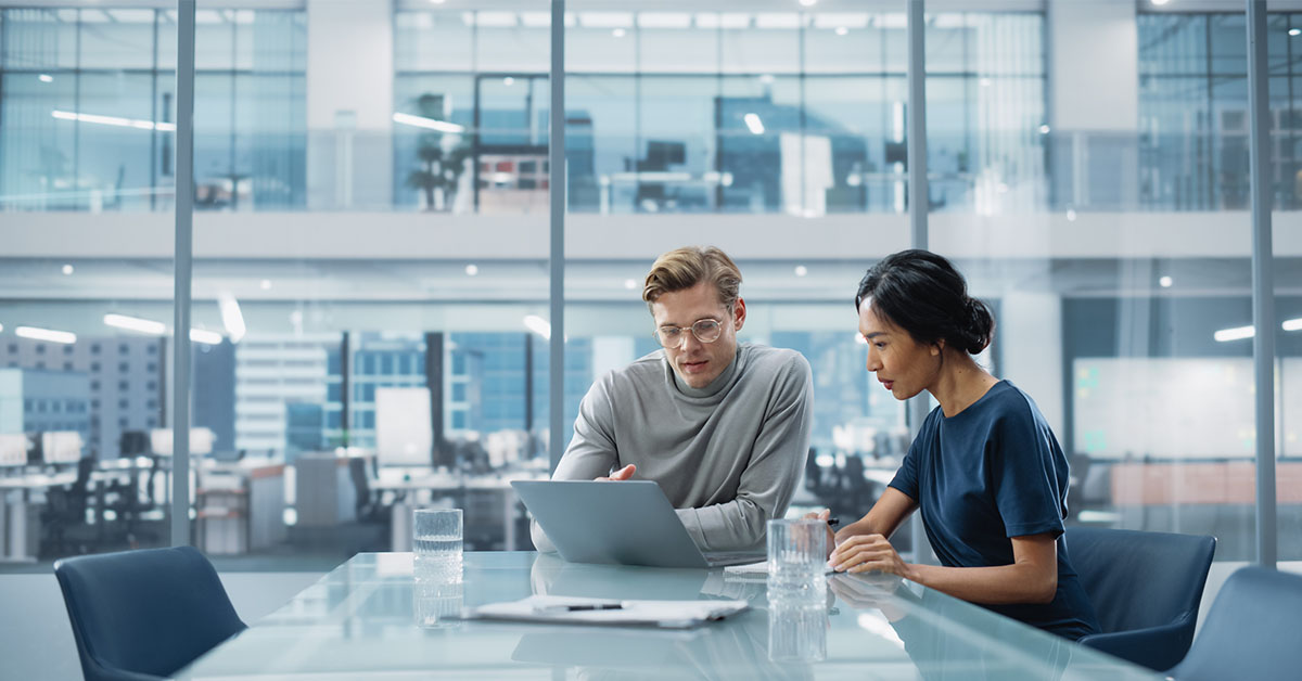 外資系IT企業の女性営業担当者が、海外出身の同僚と打ち合わせをする様子を捉えた、多国籍チームでのコミュニケーション力が伝わるシーン。