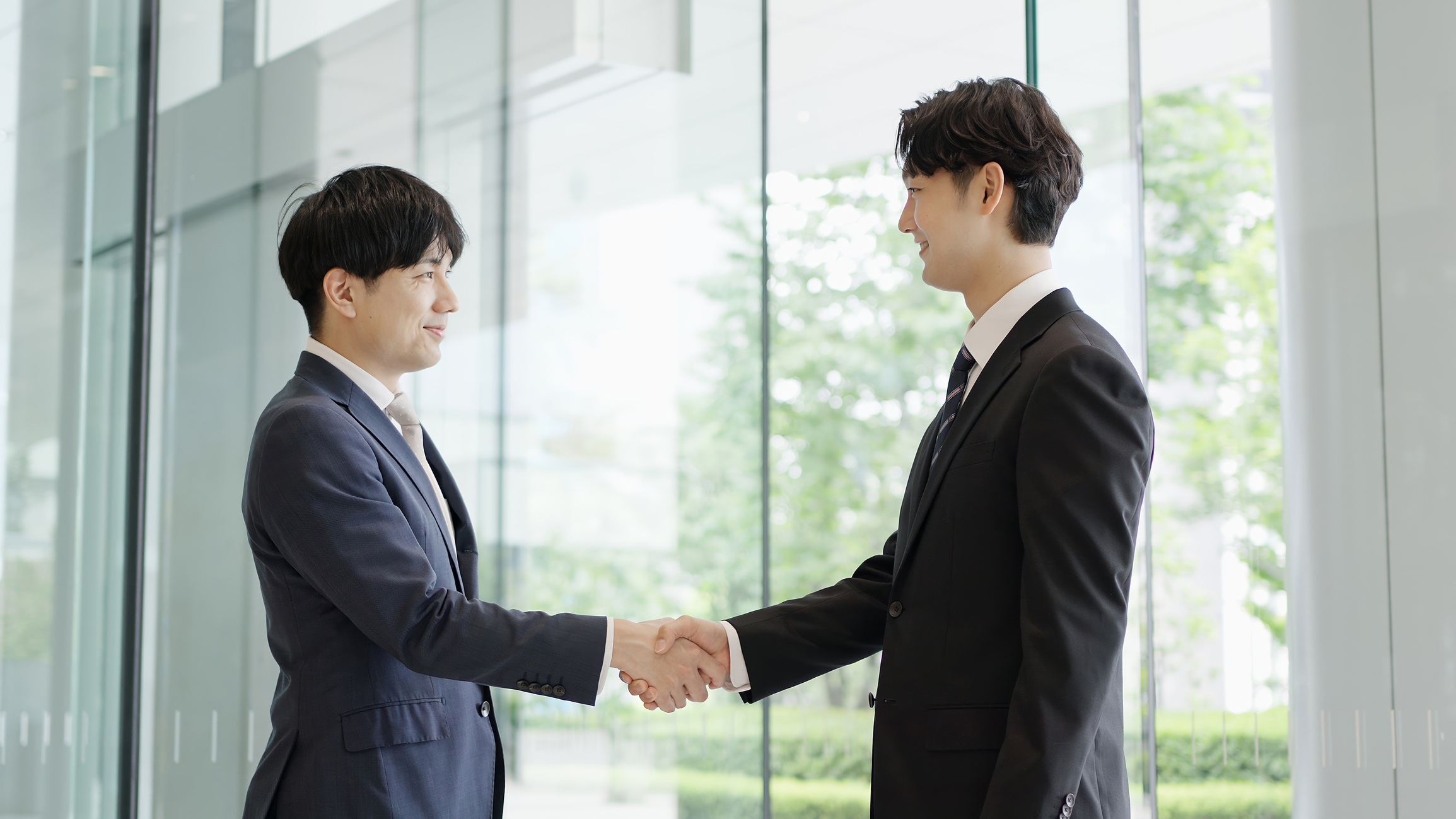 自己評価を通じて転職を成功させ、社内の信頼関係を深めるビジネスマン2人が握手するイメージ