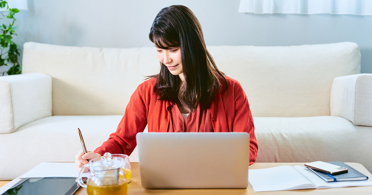 自宅でノートパソコンを使い、スタートアップ転職前の情報収集と自己分析を行う女性。