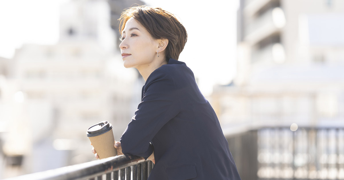 コーヒーを片手に屋上で会社を辞めようか考えている日本人女性