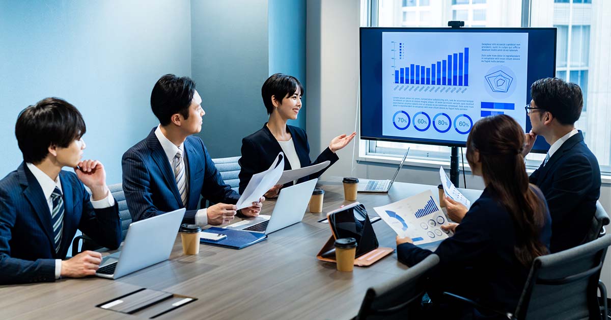 外資系IT企業のエンタープライズセールス担当者が、同僚と顧客を前にプレゼンする様子。