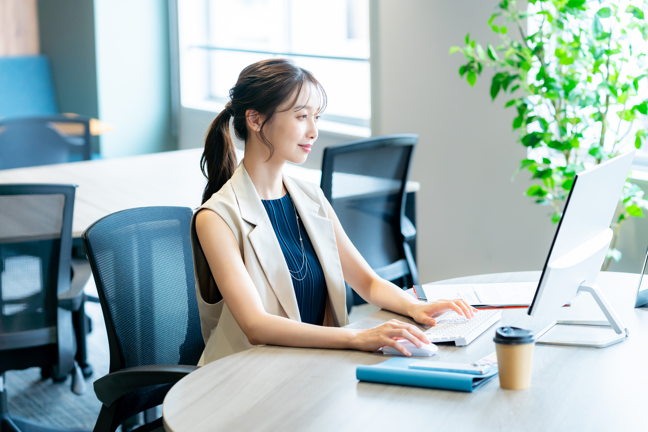 コワーキングスペースのデスクでスタートアップ企業への転職後に柔軟なリモートワークを行う女性。