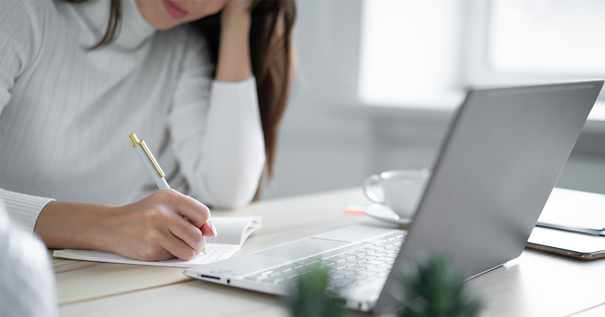 転職活動で自己PRが書けないと悩む女性が、ノートPCの前で考え込んでいる様子