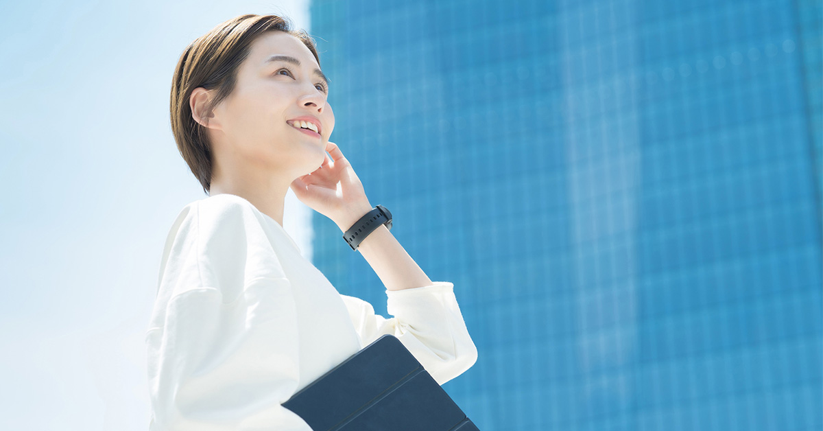 自分の市場価値を知り、転職でキャリアアップや年収向上、適切な求人選びの可能性を見据え、タブレットとスマホを手に微笑むビジネス女性。