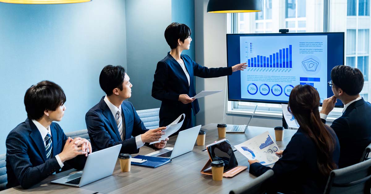 FP&A担当の女性が会議で財務データのグラフを使ってプレゼンしている様子
