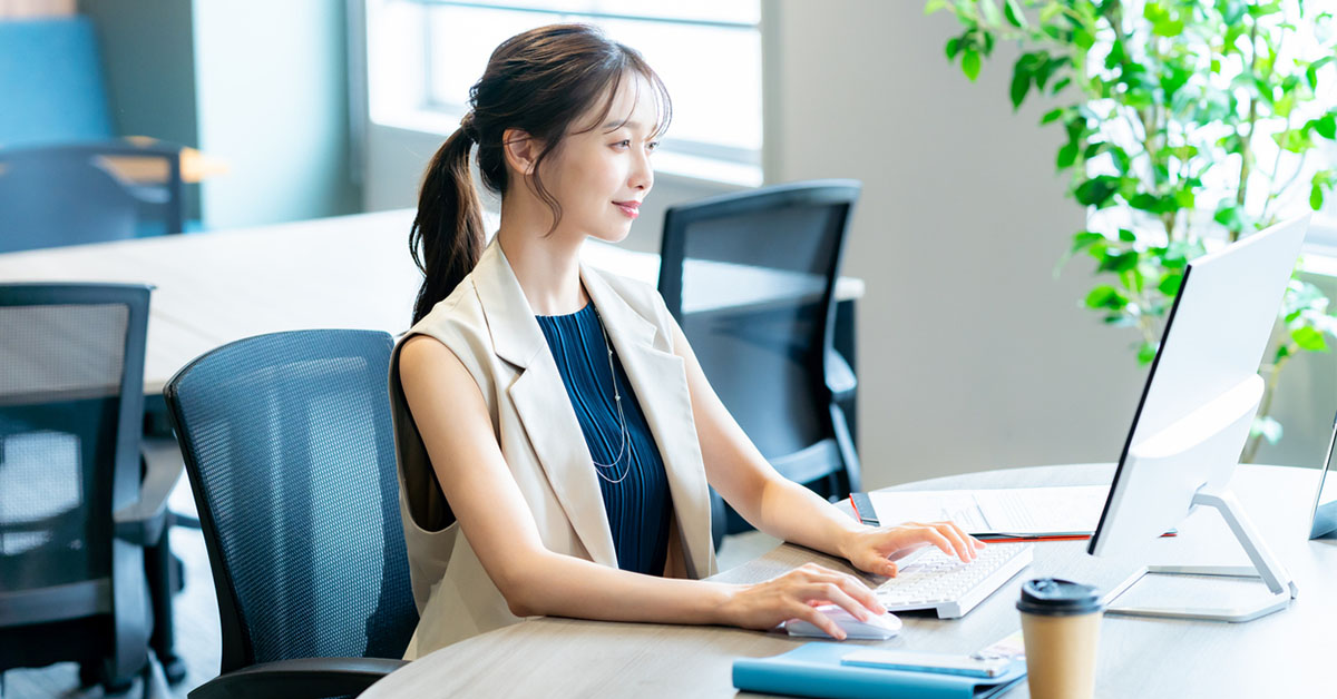 コワーキングスペースのデスクでスタートアップ企業への転職後に柔軟なリモートワークを行う女性。