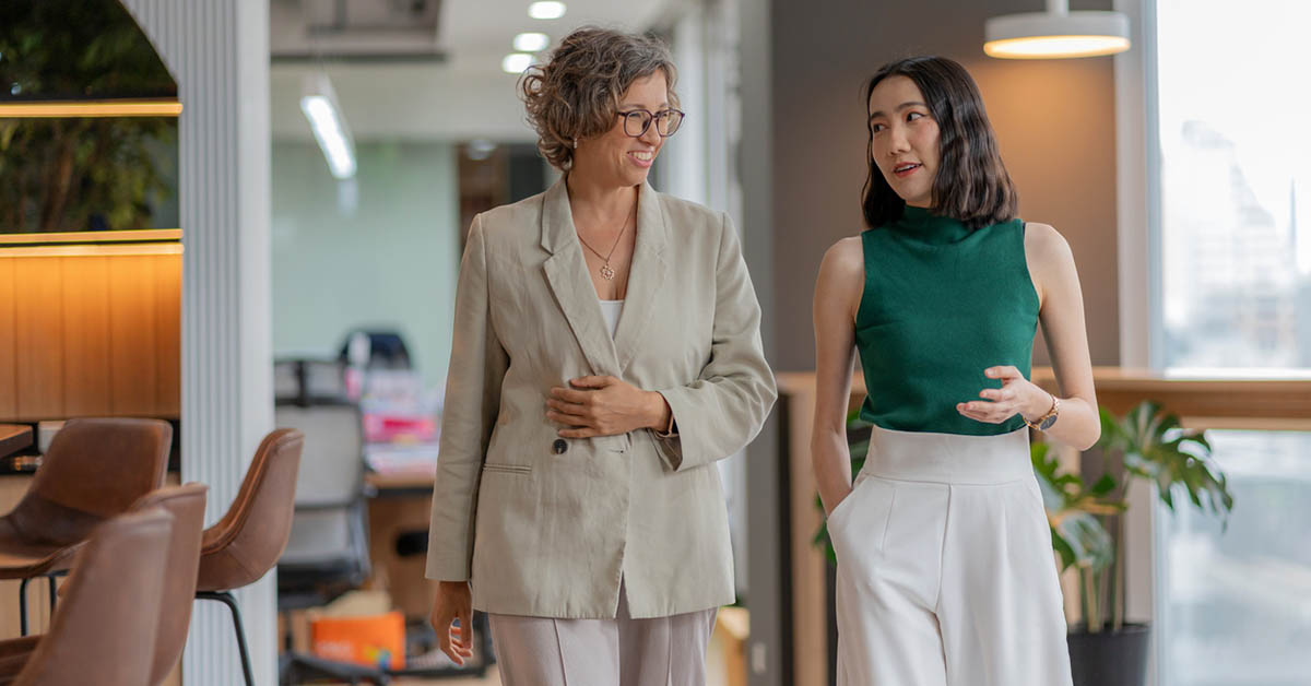 外資系企業で働く多様なビジネスパーソンがオフィス内を歩きながら会話している様子