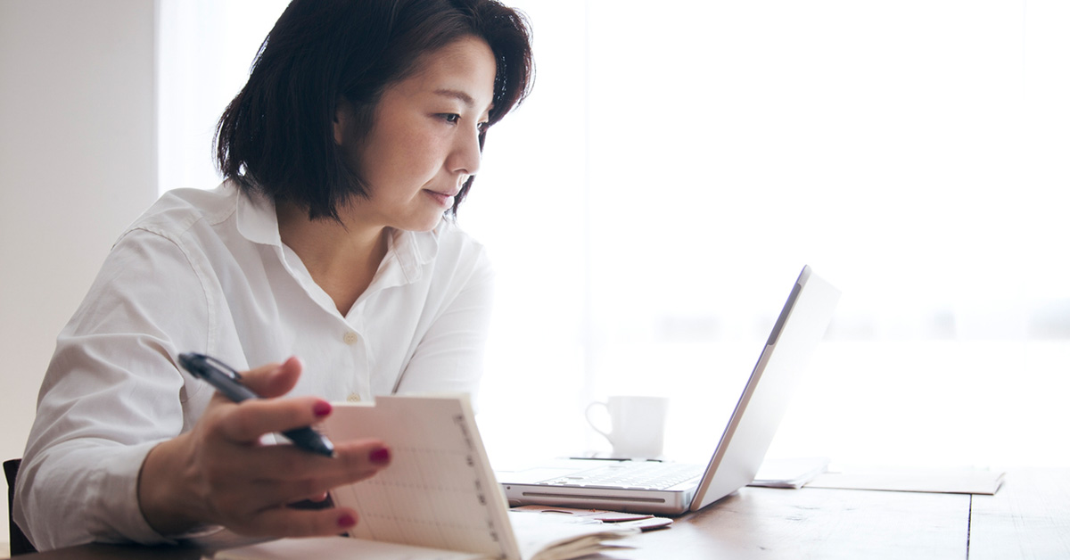 ノートとパソコンを手元に自分の適性や目指す方向を整理する女性の様子