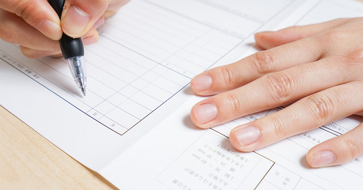デスクの上の白紙の履歴書を前に、ペンを持ったまま自己PRに悩む人のイメージ