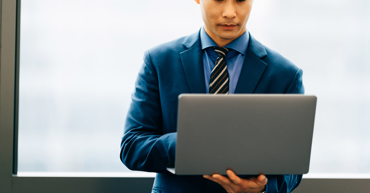 内部統制や内部監査のチェックを行う日本人男性がスーツ姿でパソコンを操作している様子