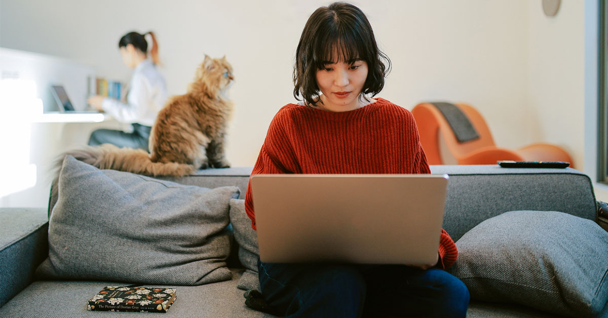年末年始の休暇に猫とソファで転職準備をする女性