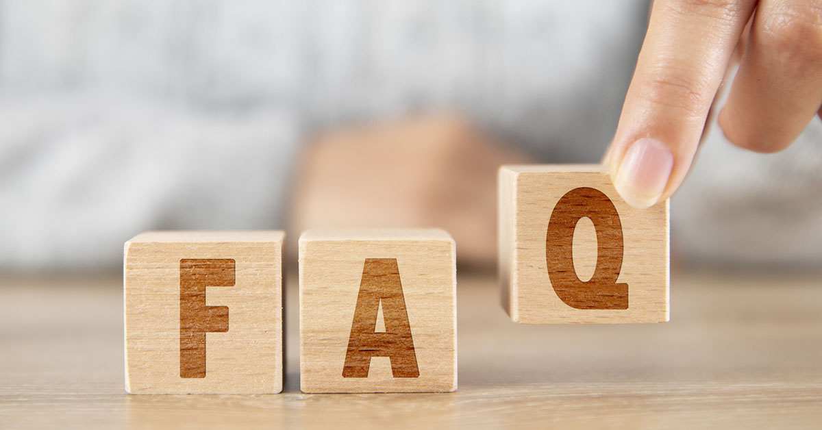 Wooden blocks spelling 'FAQ' with a finger lifting the 'Q' block