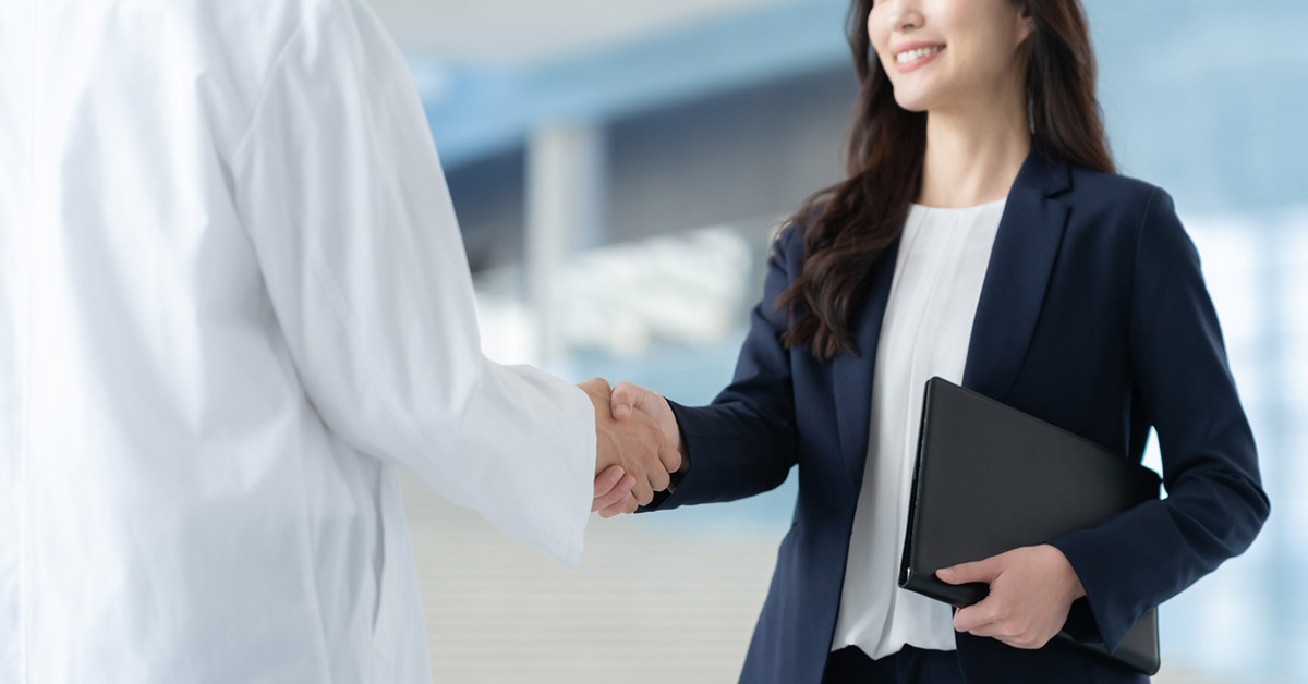製薬業界における転職成功とキャリア戦略を象徴する、医療従事者とビジネスパーソンの握手シーン