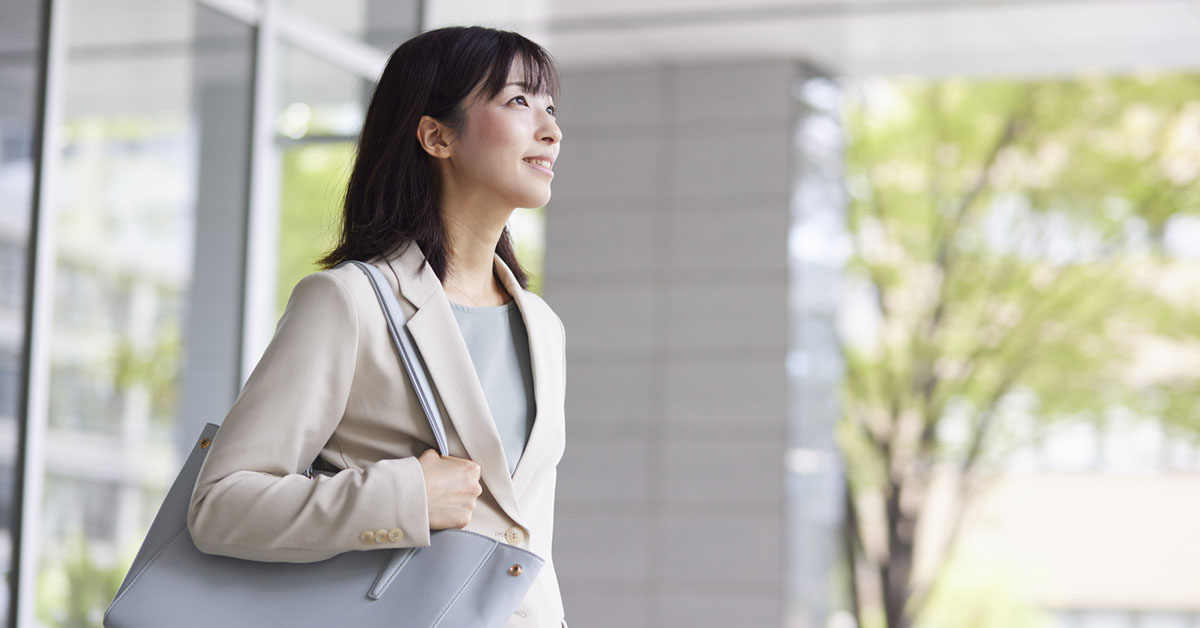 オフィスビルの中を歩くビジネス服の女性｜病院以外で働くキャリアのイメージ