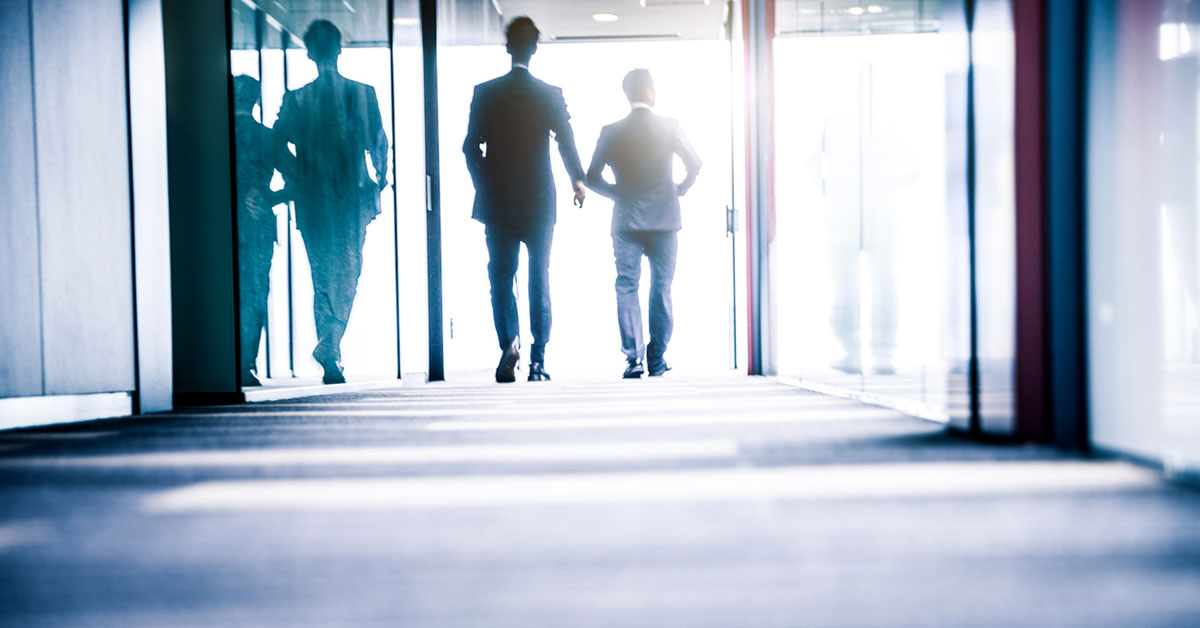 Two senior business executives walking in a corporate office corridor, representing C-level leadership hiring in Japan.
