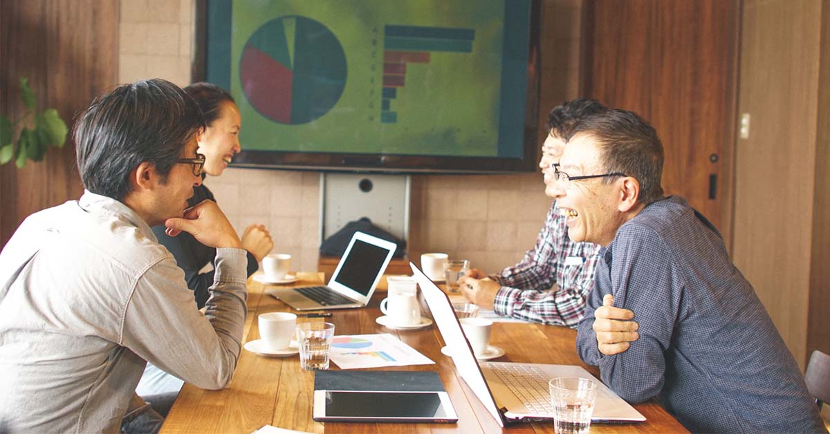 管理職未経験だが小さなチームのリーダーとしての経験がある40代男性がチーム会議を楽しく行うシーン