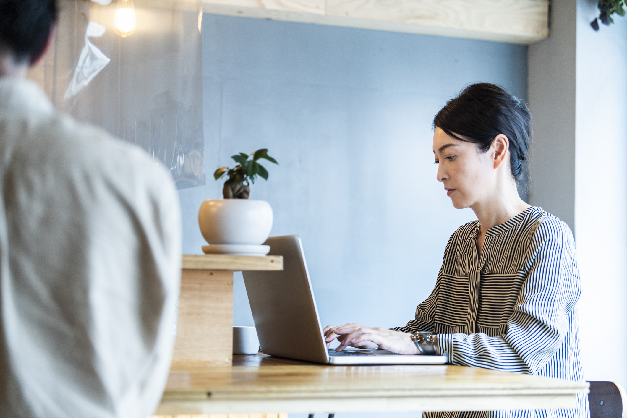 転職を考えながらオフィスでノートパソコンに向き合う40代女性ビジネスパーソンのイメージ