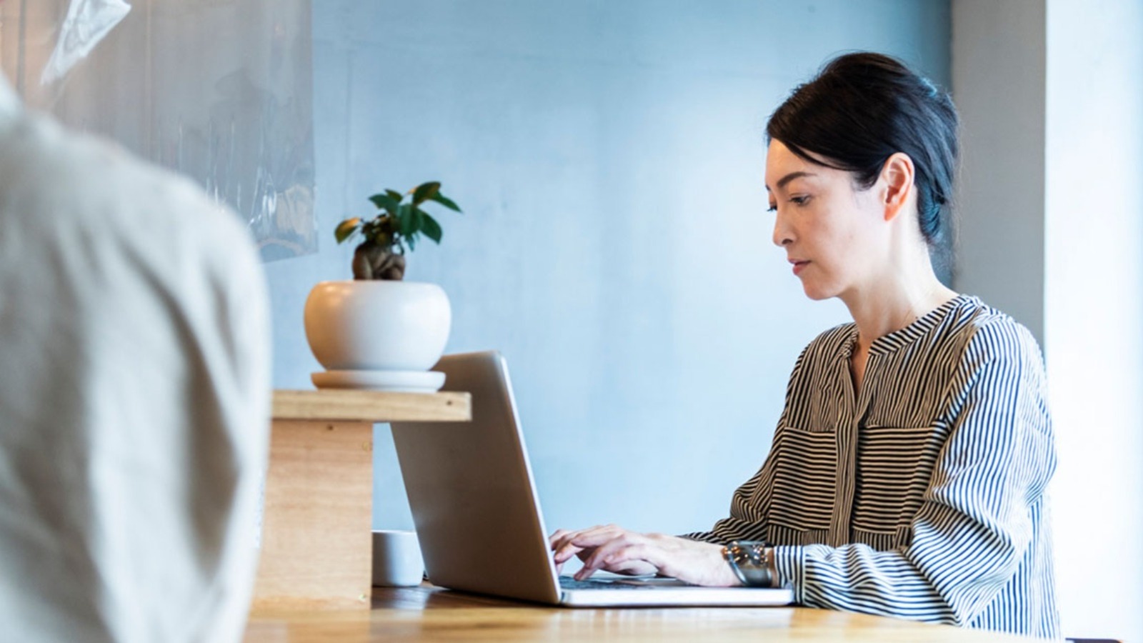 転職を考えながらオフィスでノートパソコンに向き合う40代女性ビジネスパーソンのイメージ